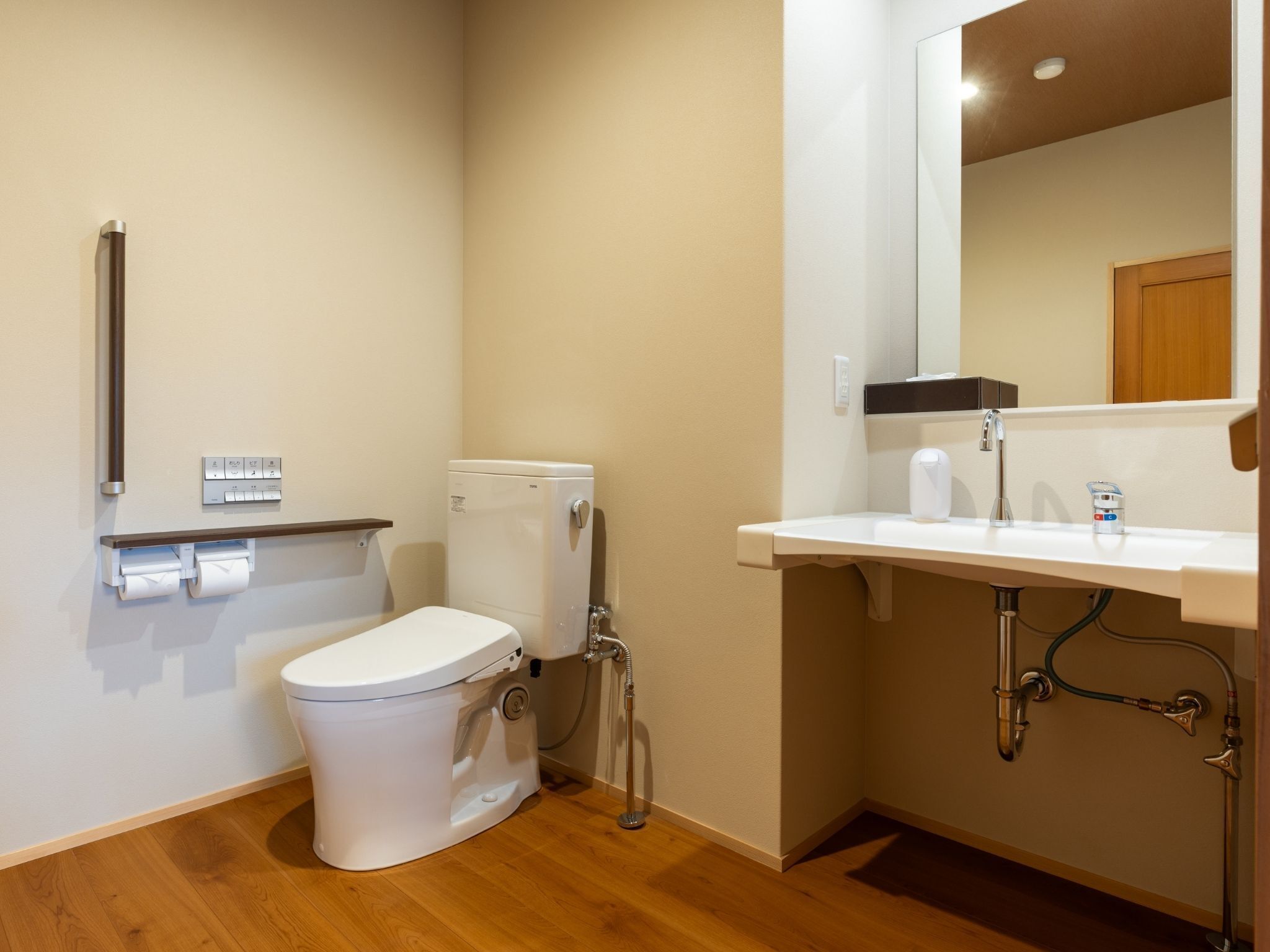 A small, compact bathroom with a toilet, a sink, and a mirror.