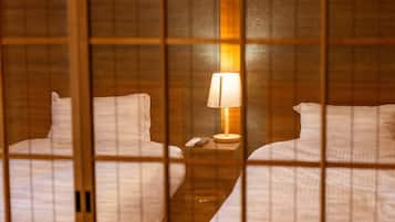 Una camera d'albergo con due letti, un comodino con una lampada e un telecomando.