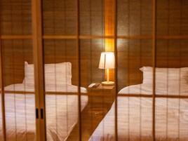 Habitación de hotel con dos camas, una mesita de noche con lámpara y un control remoto.