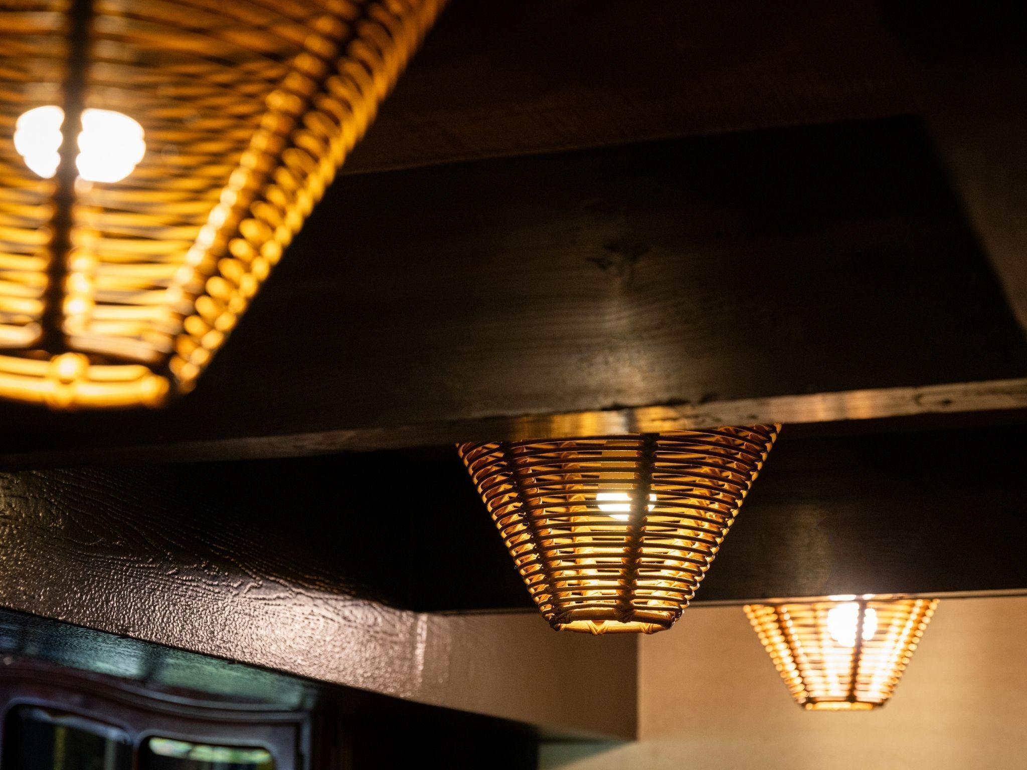 A ceiling with a woven light fixture and a wall with a textured surface.