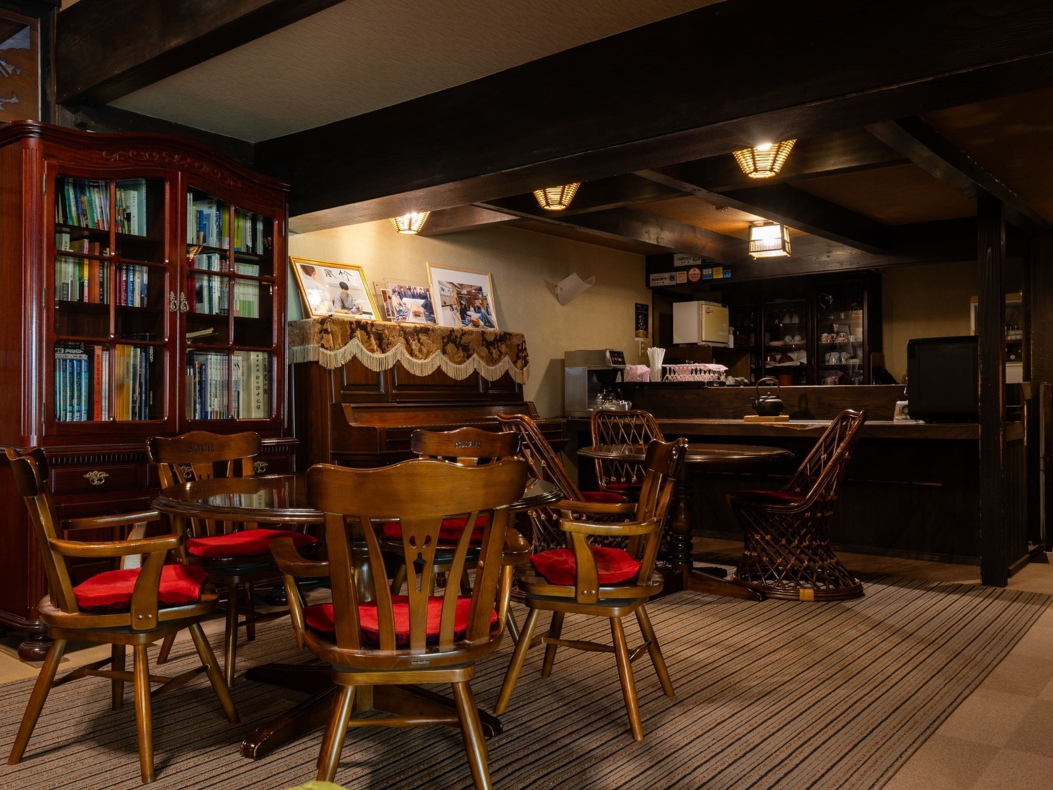 A cozy room with a wooden bookshelf, a piano, and a dining area with chairs.