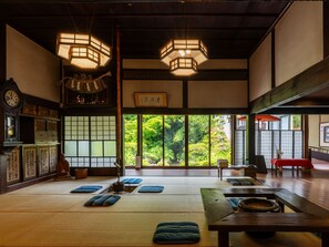 A traditional Japanese room with tatami flooring, a shoji screen, and a view of greenery outside. - Koshinoyado Takashimaya (Niigata)