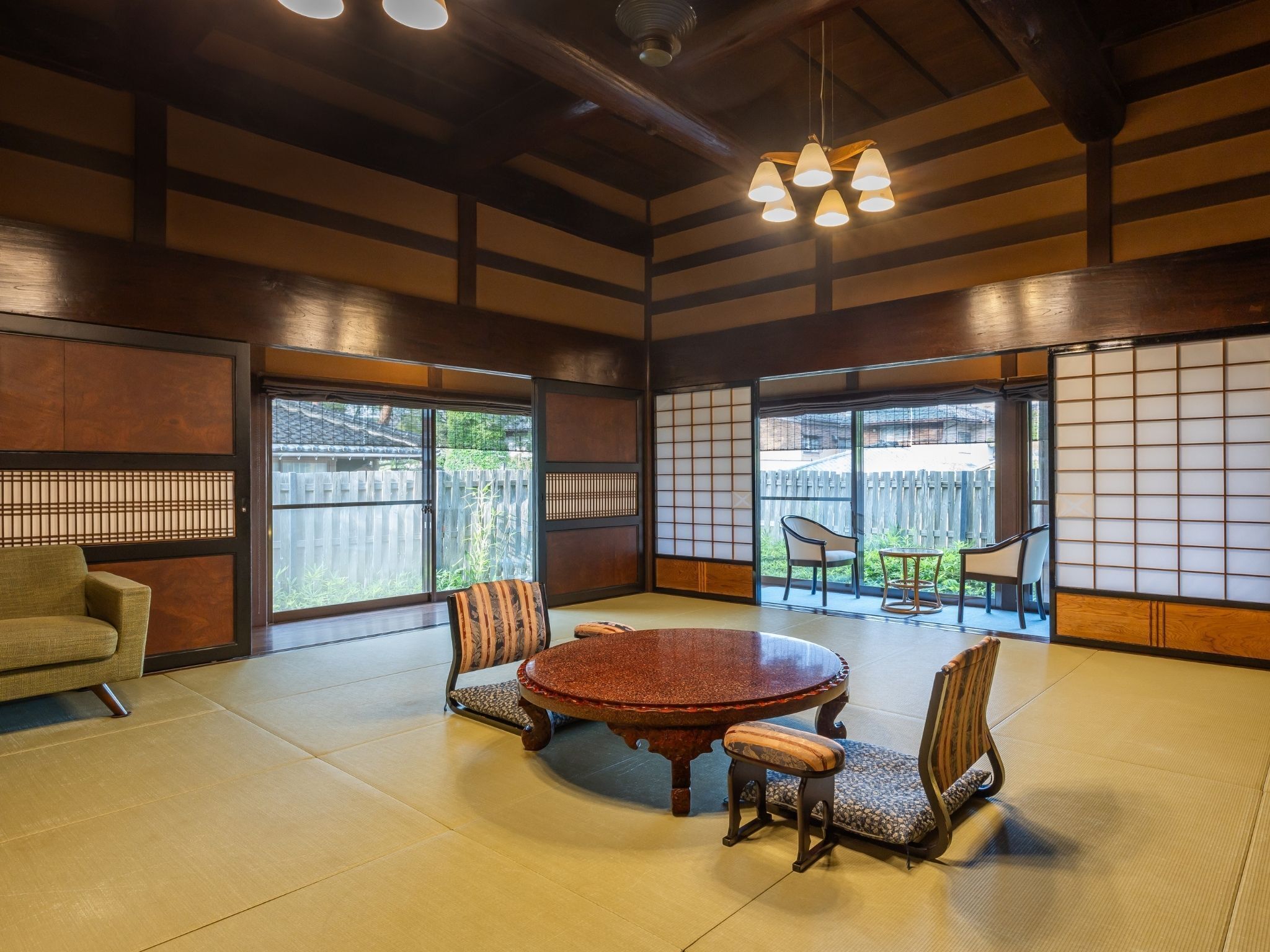 A traditional Japanese-style room with tatami flooring, a round table, and low wooden chairs.