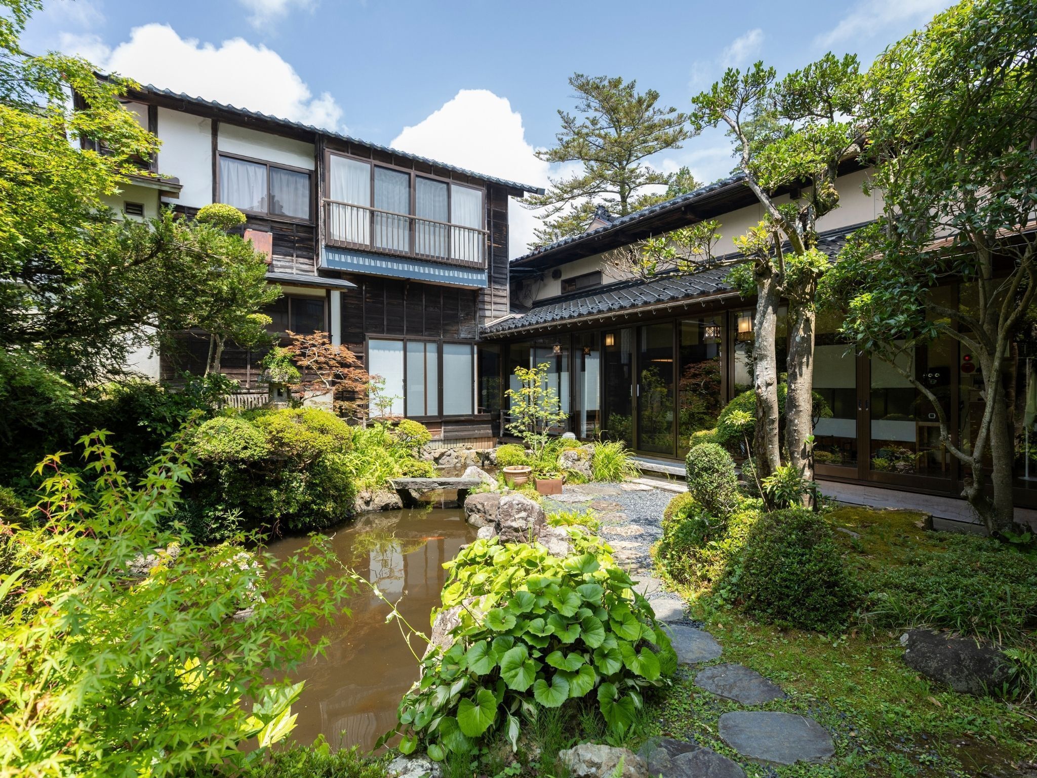 A traditional Japanese-style building with a koi pond and lush greenery.