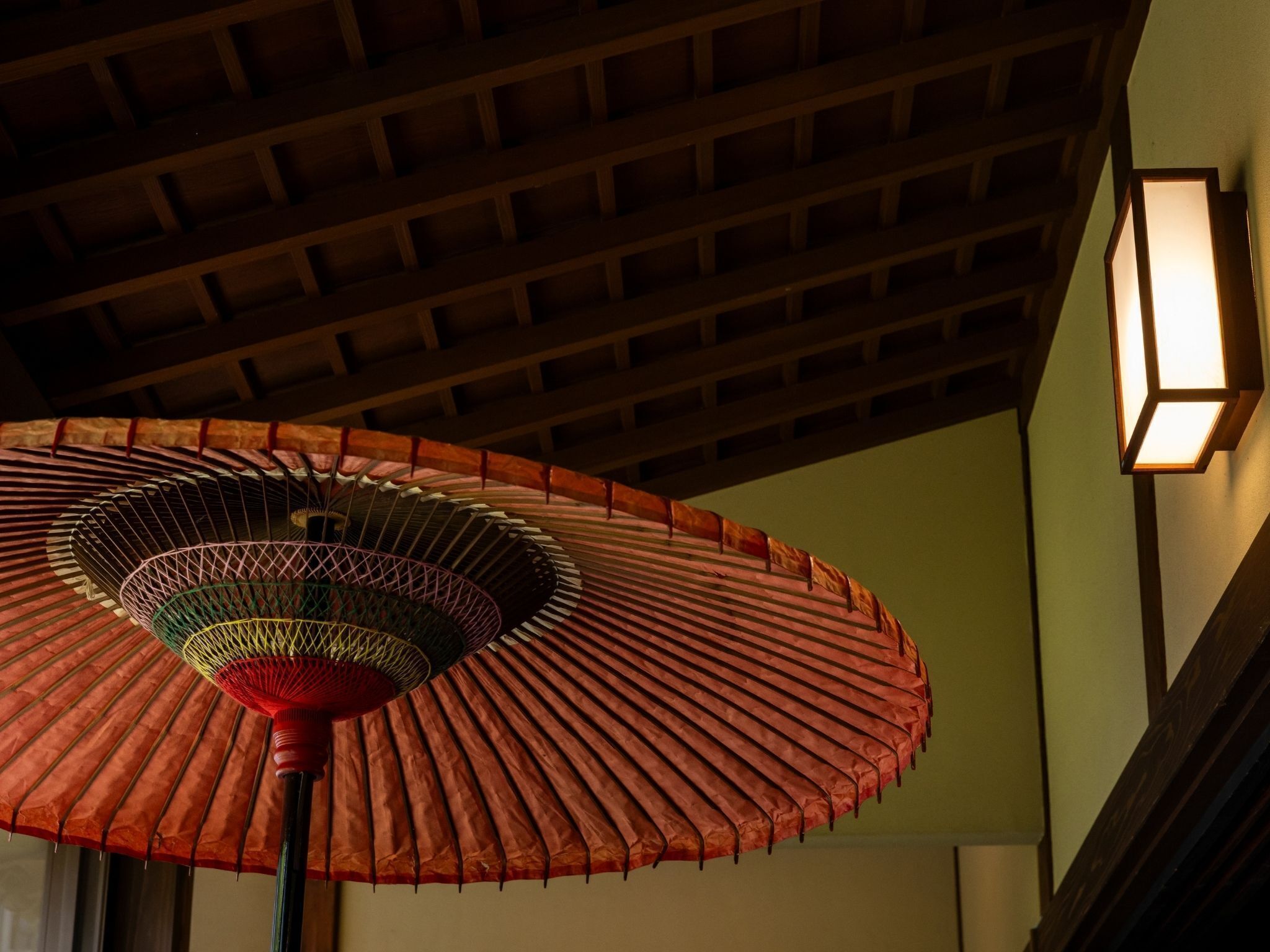 A traditional Japanese room with a wooden ceiling and a hanging decorative umbrella.