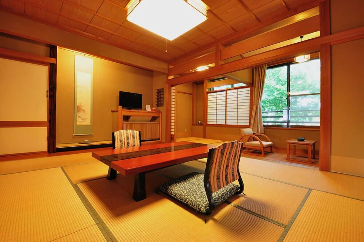 A traditional Japanese room with tatami flooring, a low table, and a cushioned chair.