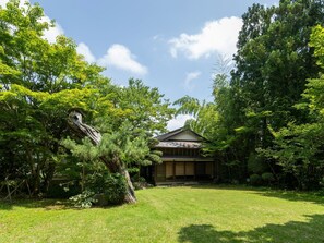 Ein traditionelles japanisches Haus, umgeben von üppiger Vegetation.