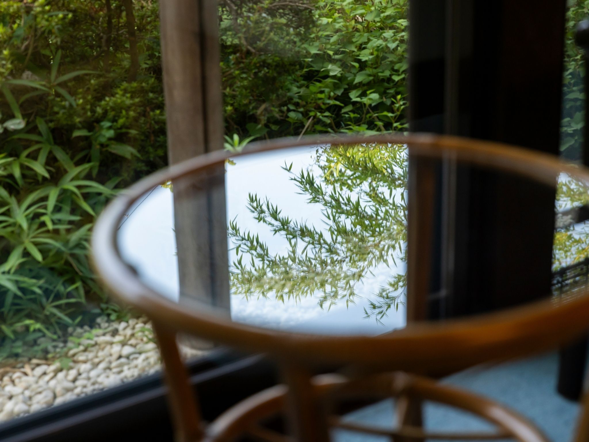 Una mesa de vidrio redonda con vista a la vegetación por la ventana.