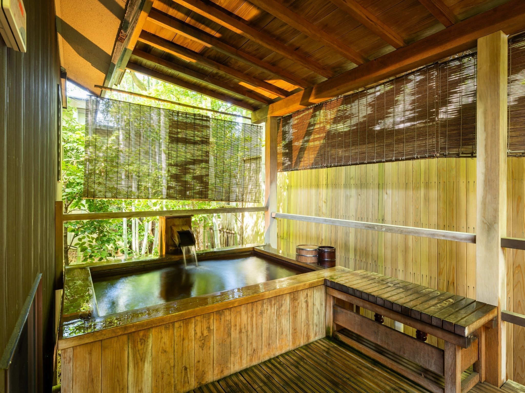 A traditional wooden hot spring bath with a wooden bench and a small wooden structure.