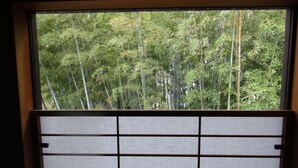Habitación con vista a un bosque de bambú a través de una ventana con panel japonés shoji.