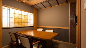 Un salón de conferencias con una mesa y sillas de madera, un ventanal grande y una puerta corredera tradicional japonesa.