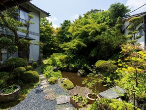 Ein traditioneller japanischer Garten mit einem Koiteich, Steinwegen und verschiedenen Pflanzen.