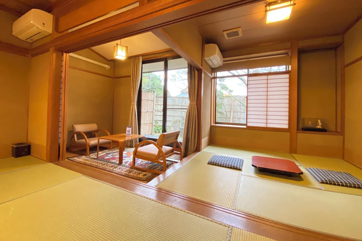 A traditional Japanese room with tatami flooring, a low table with chairs, and sliding doors.
