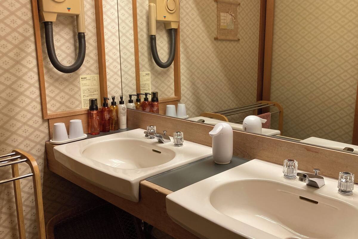 A hotel bathroom with two sinks, a mirror, and toiletries.