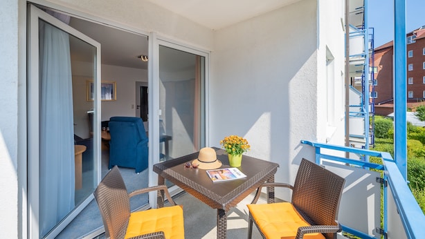 A balcony with a table, chairs, a hat, and a flower vase. - Haus Strandruh (Binz)