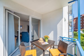 A balcony with a table, chairs, a hat, and a flower vase. - Haus Strandruh (Binz)