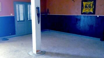 Un estacionamiento vacío con pisos y paredes de concreto, una puerta con persianas y un letrero en la pared.