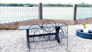 Ein Sitzbereich im Freien mit Metallstühlen und einem Tisch, einer kleinen Pflanze und einem Reifen-Pflanzgefäß.