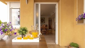 A dining area with a wooden table set for breakfast, a pitcher of orange juice, and potted plants.