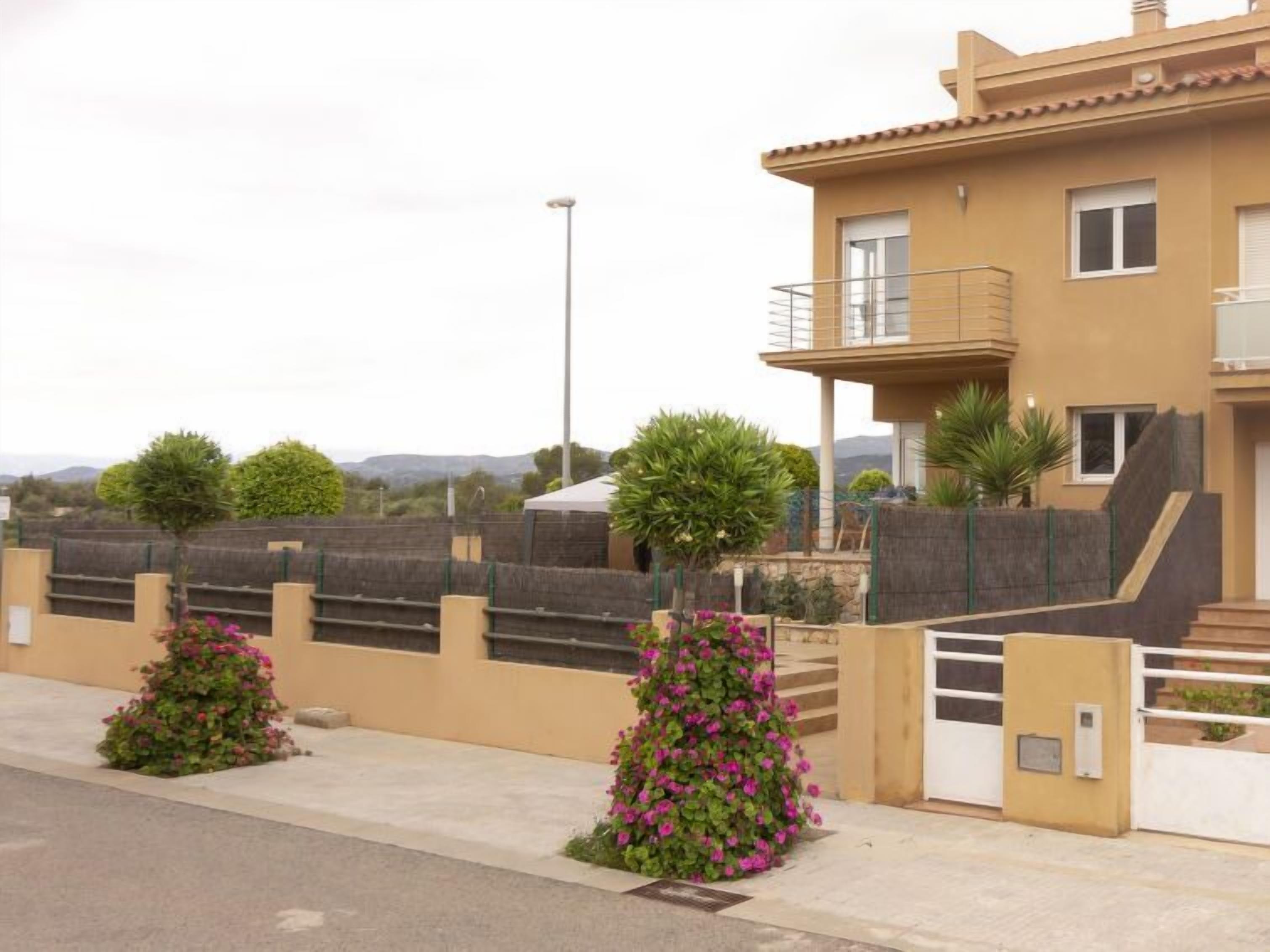 A residential building with a balcony, a gated entrance, and a view of the surrounding landscape.