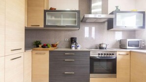 A modern kitchen with wooden cabinets, a built-in stove, a microwave, and a coffee maker.
