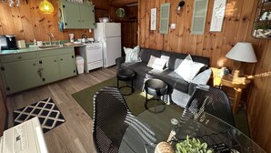 A compact kitchen with a refrigerator, stove, and hanging light fixture.