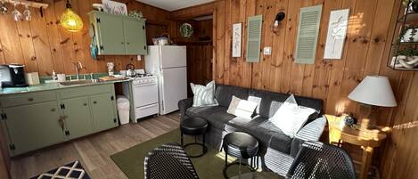 A compact kitchen with a refrigerator, stove, and hanging light fixture.