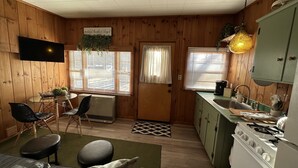 A cozy cabin-style room with a dining area, a kitchenette, and a living space.
