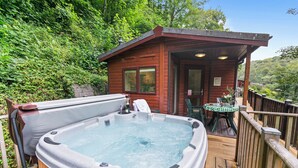 Ein Whirlpool auf einer Holzterrasse mit einer Holzhütte im Hintergrund.