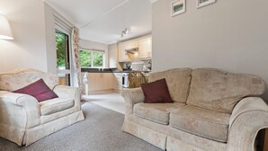 Ein Wohnzimmer mit zwei beigen Sofas, einem Couchtisch und einem Fenster mit Vorhängen.