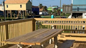A wooden deck with picnic tables and benches. - “THE SALTY OLIVE"  SHORT WALK TO THE BEACH, FUR BABIES WELCOMED (Bolivar Peninsula)
