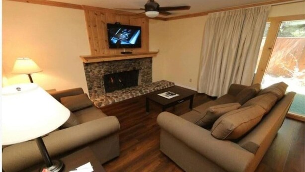 A living room with a fireplace, a television mounted above it, and a sofa set.