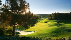 Campo de golf con búnkeres de arena, árboles y cielo despejado.