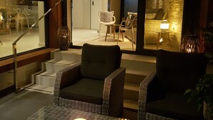 Un salón moderno con mobiliario de mimbre, una mesa de centro de vidrio y una araña.