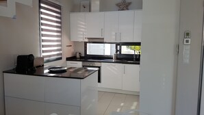 Una cocina moderna con armarios blancos, encimera negra y ventana con persianas.