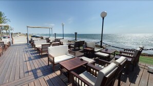 Eine Holzterrasse mit Sitzgelegenheiten und Blick auf das Meer.