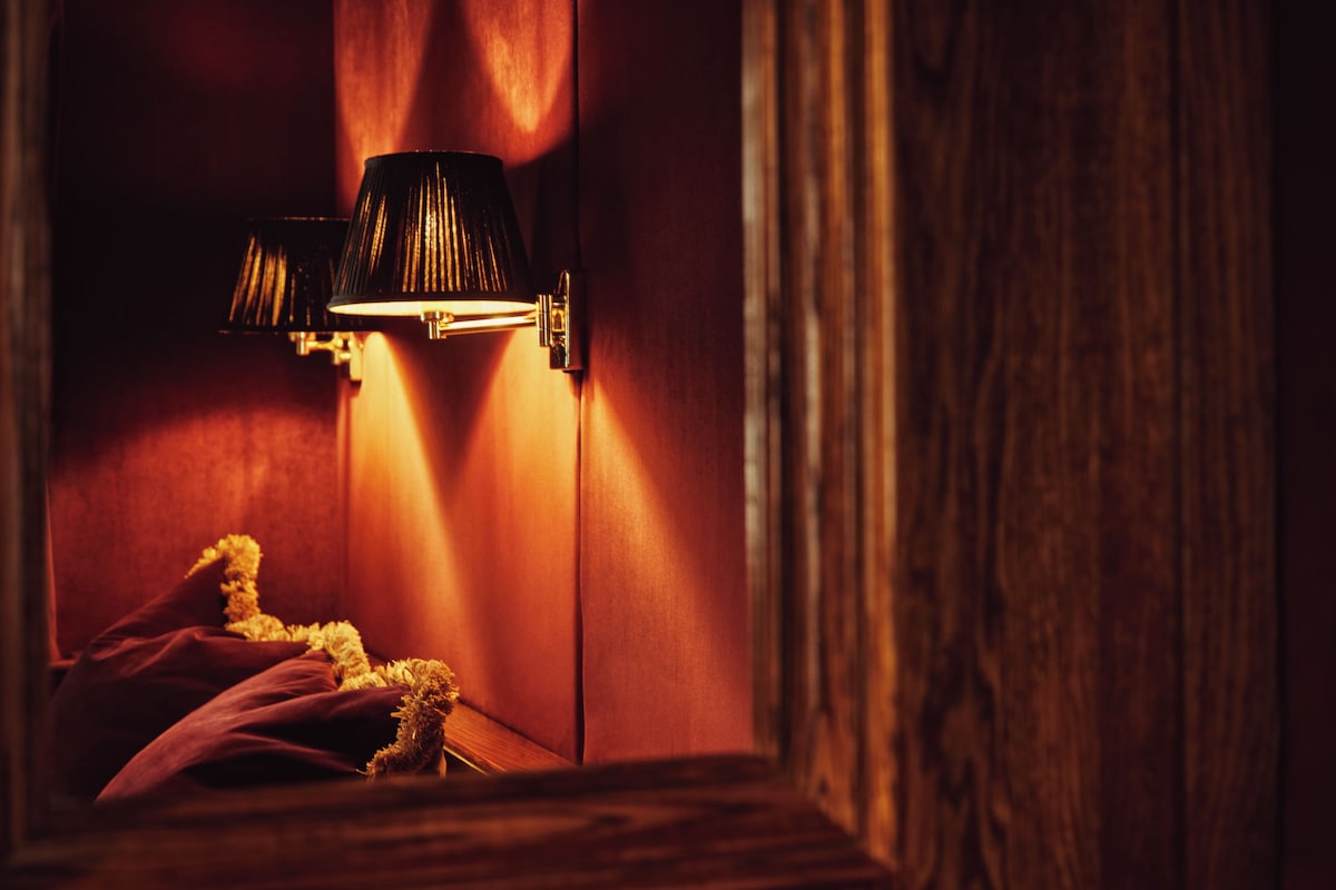 A dimly lit room with a lamp casting shadows on the wall.