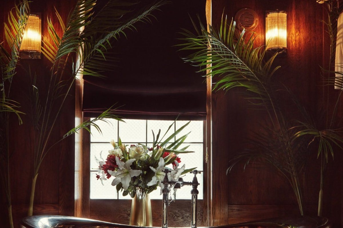 A bathroom with a freestanding bathtub, a window with a view, and decorative lighting.