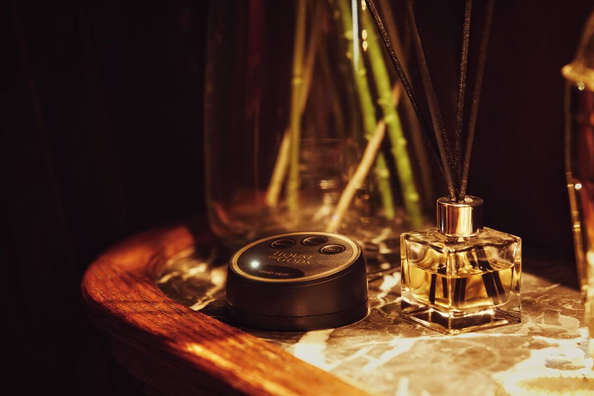 A wooden tray with a perfume bottle and a small black device on it.