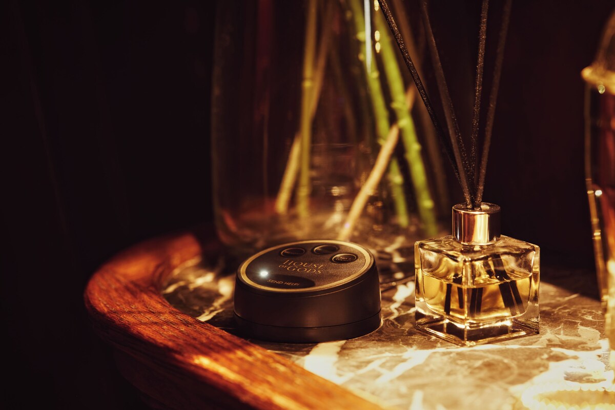 A wooden tray with a perfume bottle and a small black device on it.