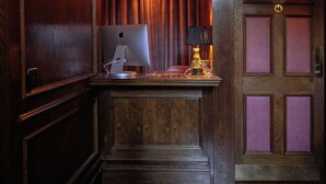 Uma mesa de madeira com um iMac da Apple, uma luminária e um queimador de incenso pequeno.