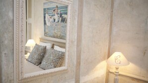 A bedroom with a bed, two pillows, a nightstand with a lamp, and a painting on the wall. - Le Manoir Du Poul Coeur de Bretagne B&B (Mellionnec)