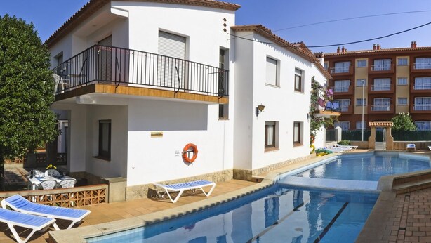 Ein zweistöckiges Gebäude mit Pool, Balkon und Blick auf ein größeres Gebäude im Hintergrund.