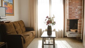 Ein Wohnzimmer mit einer Couch, einem Tisch mit einer Vase, einem Kamin und einem Gemälde an der Wand.