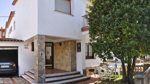 Ein modernes, zweistöckiges Haus mit Naturstein-Fassade, einer Garage und einer Terrasse mit Gartenmöbeln.