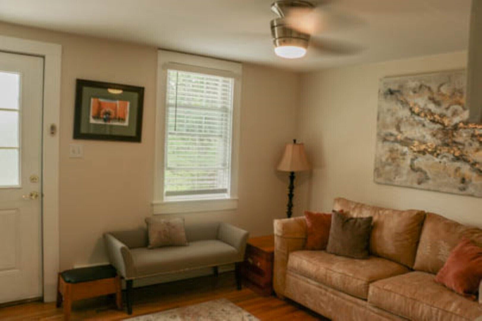 A living room with a sofa, a bench, a lamp, and a painting on the wall.