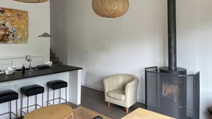 A modern kitchen with a bar area, a white chair, and a black fireplace. - Contemporary chalet with exceptional views and exposure 4 minutes from St Lary Soulan (Estensan)