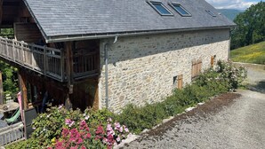 A stone building with a sloped roof, wooden balcony, and a gravel driveway. - Contemporary chalet with exceptional views and exposure 4 minutes from St Lary Soulan (Estensan)