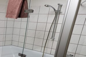 Een bad/douchecombinatie, handdoeken