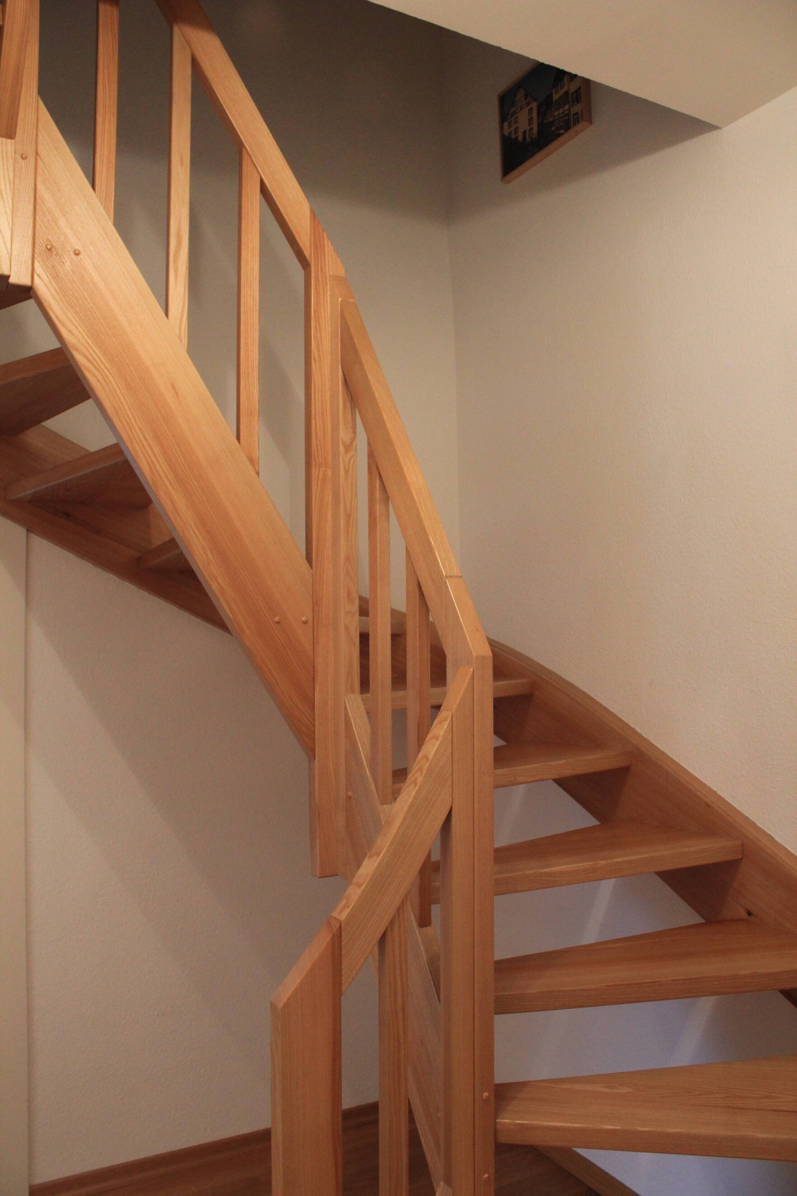 Una escalera de madera con barandilla y un pequeño adorno en la pared.